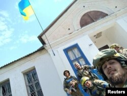 Солдаты фотографируются на фоне украинского флага в освобожденном селе Василенково Харьковской области, 10 сентября 2022 года