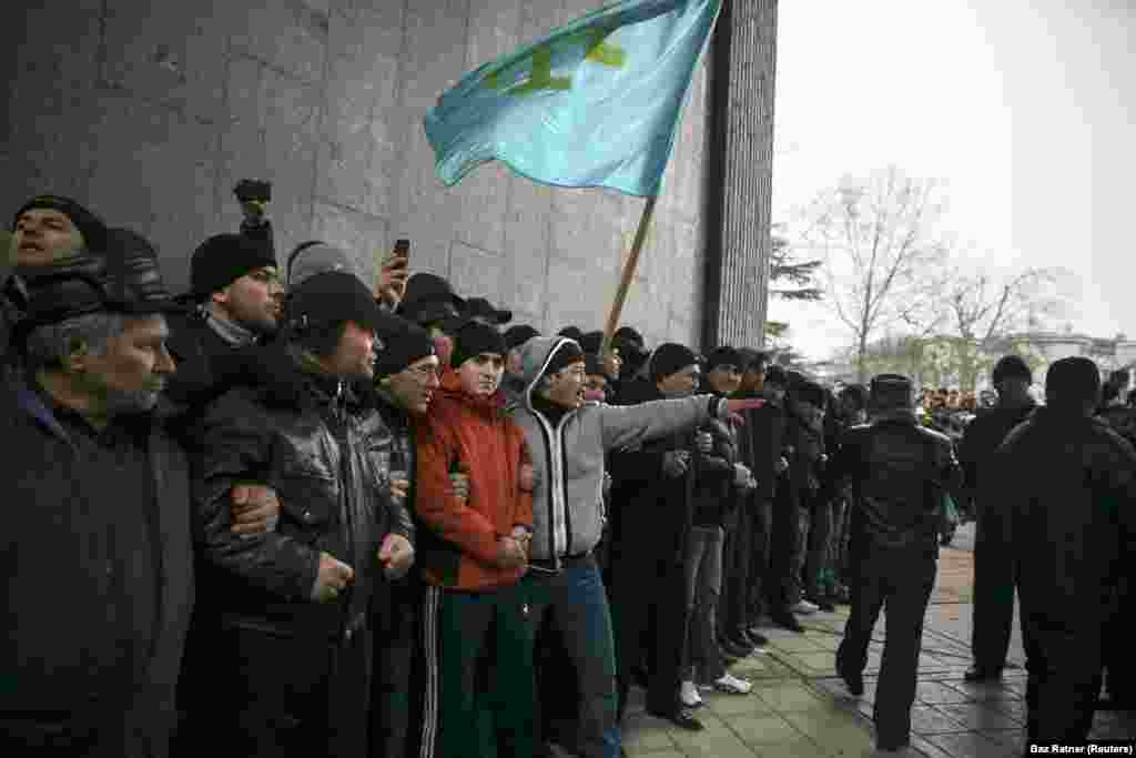 Крымские татары со своим флагом на митинге у парламента Крыма в Симферополе, 26 февраля 2014 года. Неделей ранее глава парламента Крыма поднял вопрос о возможности &laquo;отсоединения&raquo; полуострова от Украины. В это время в Киеве проходили массовые демонстрации с требованием отстранения от власти пророссийского президента Виктора Януковича, украинцы позже назвали эти события &laquo;революцией достоинства&raquo;