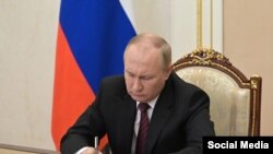 Vladimir Putin signs a document