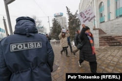 Активисты движения Oyan, Qazaqstan проходят мимо сотрудника полиции