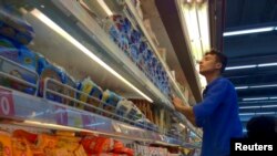 Человек у холодильника выбирает продукты. Иллюстративное фото.