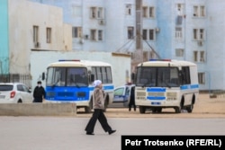 Жаңаөзеннің орталық алаңындағы полиция автобустарының жанынан өтіп бара жатқан әйел. Маңғыстау облысы, 16 желтоқсан 2021 жыл