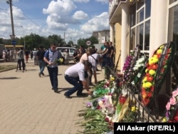 Жители Актобе несут цветы к зданию оружейного магазина, где произошло одно из первых убийств 5 июня. Актобе, 8 июня 2016 года.