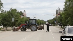 Полицейский блокирует улицу на месте спецоперации против подозреваемых боевиков. Актобе, 10 июня 2016 года.