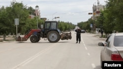 Полицейский блокирует улицу на месте спецоперации против подозреваемых боевиков. Актобе, 10 июня 2016 года.