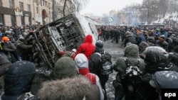 Протестующие опрокидывают сгоревший автобус, принадлежащий МВД. Киев, 21 января 2014 года.