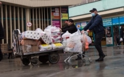 Көк базар маңында дәретхана қағазы мен азық-түлік тиелген арбаны сүйреп келе жатқан адам. Алматы, 18 наурыз 2020 жыл.