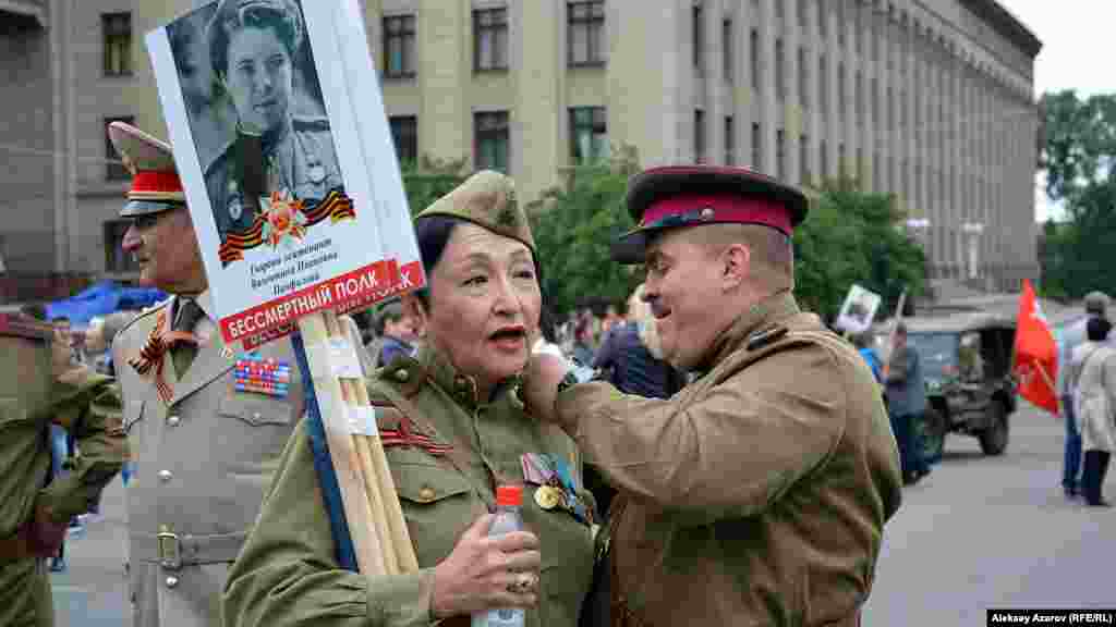 Ветеран боевых действий в Афганистане полковник Сергей Пашевич что-то прикрепляет к погону на гимнастерке Алуа Байкадамовой &ndash; внучки знаменитого командира 316-й стрелковой дивизии Ивана Панфилова. Она и он одеты в форму Красной армии времен Великой Отечественной войны.&nbsp;