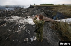 Пророссийский боевик фотографирует место крушения лайнера Boeing 777 авиакомпании Malaysia Airlines. Донецкая область, 17 июля 2014 года.