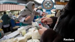 Покупатель у прилавка с молочной продукцией на Зеленом базаре в Алматы.