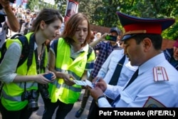 Полицейские рассматривают документы журналистов во время шествия. В центре — корреспондент казахстанского издания «Vласть.kz» Данияр Молдабеков. Алматы, 9 мая 2019 года.