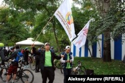 Волонтеры выдвигаются к месту старта. В руках у одного из них флаг Дня города и флаг Veloquestʼа. Алматы, 13 сентября 2015 года.