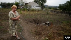 Местная жительница стоит в огороде возле упавшей ракеты. Донецкая область, 28 августа 2014 года.